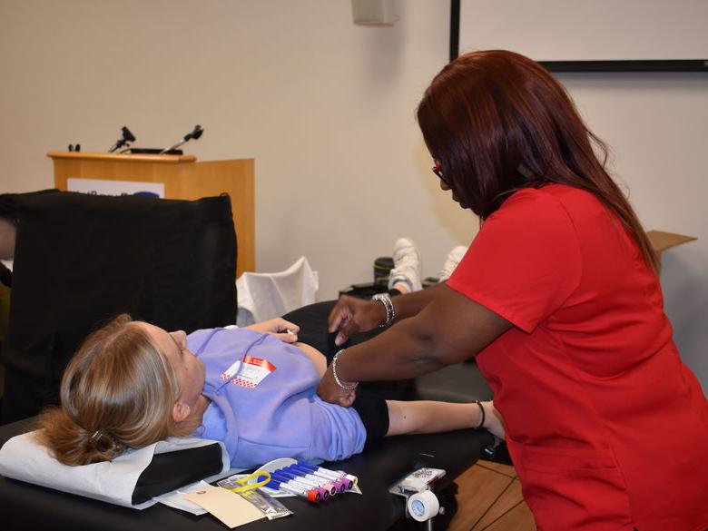 student laying on table about to get blood taken